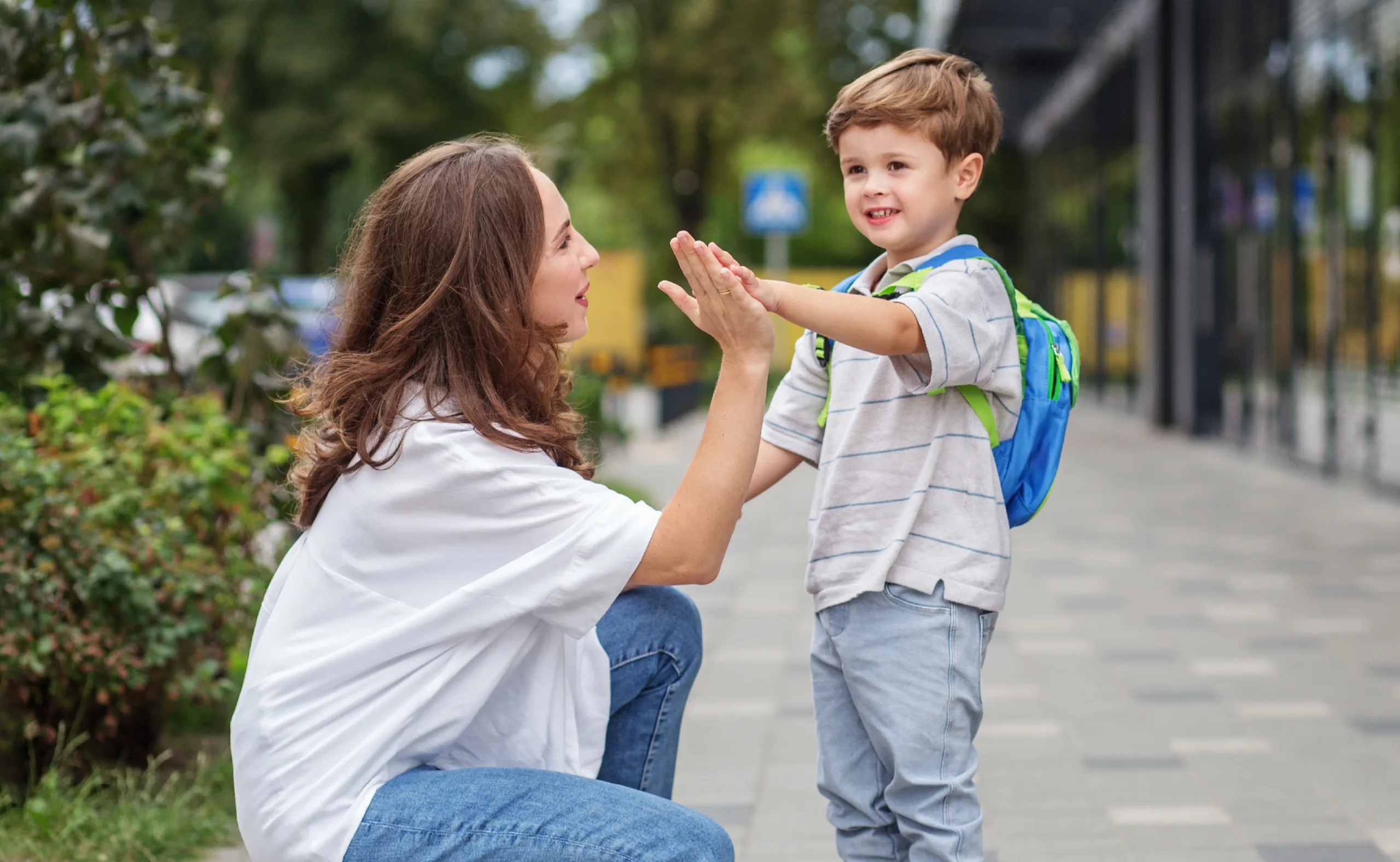 A mom sending her son to school with a good-bye high-five.