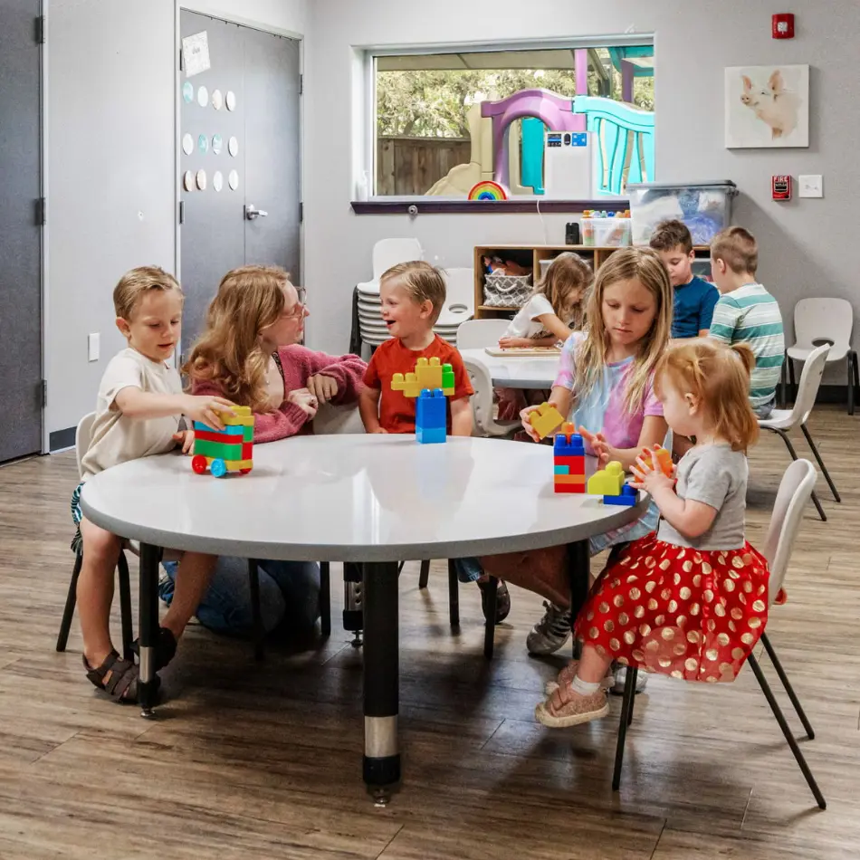 Teacher with children at table.