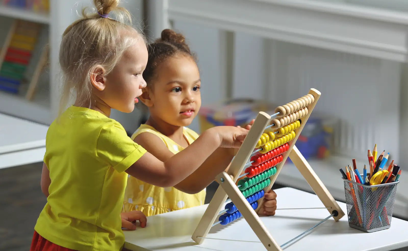 Children sit together at the table and count on the abacus.